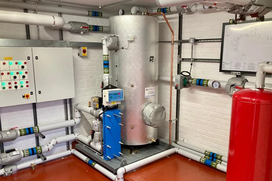 Hot-water tanks, pumps and heat-exchanger pipework in a plant room